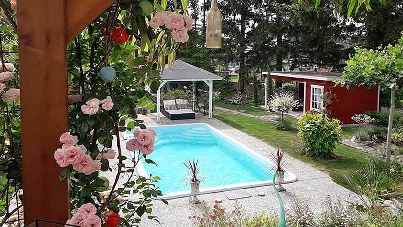 Blumen und Pool mit türkisem Wasser und Gartenhaus