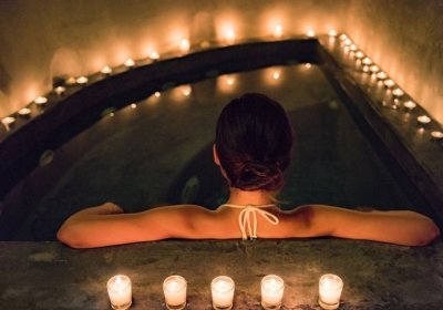 Wellness Garten gestalten: Die 10 besten Ideen für Ihre Wellness-Oase! Frau entspannt im Wasser mit Kerzen
